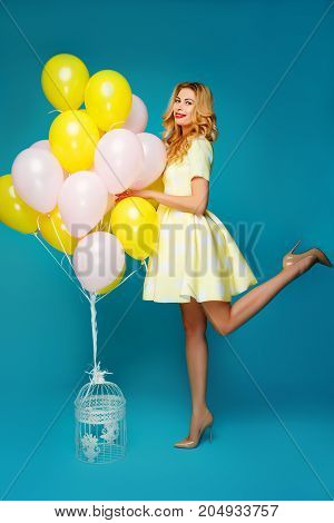 Happy smiling woman is looking on an air colorful balloons having fun.