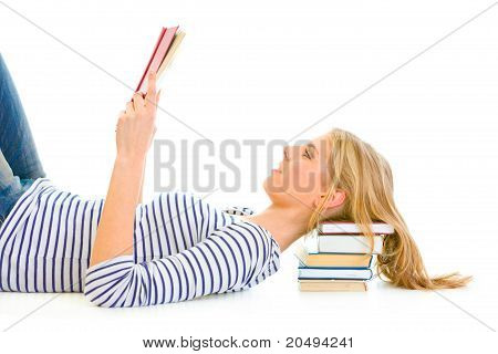 Sdraiato sul pavimento teengirl con riposo testa su pile di libri scolastici lettura isolata on white