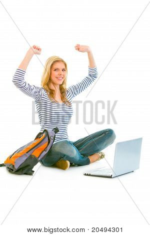 Seduto sul pavimento con zainetto e laptop lieto teengirl esultanza il suo successo isolated on white