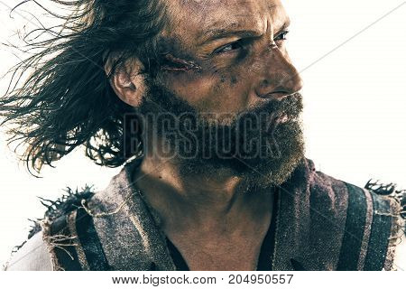 Portrait of a brutal bald-headed viking in a battle isolated against a white background. Early medieval period. Actor in makeup. concept of vagrancy and survival
