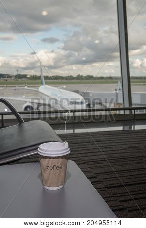 Cup Of Coffee In Airport's Business Lounge With Aircraft