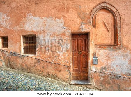 Alte Holztür im Haus und engen gepflasterten Straße in Stadt von Saluzzo, Norditalien.