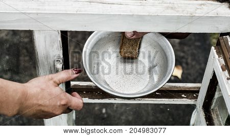 In his hand clamped aluminum plate and a piece of bread. The plate and the bread are passed through the window.