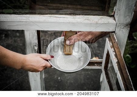 In his hand clamped aluminum plate and a piece of bread. The plate and the bread are passed through the window.