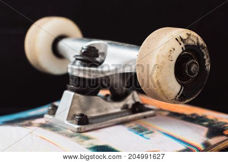 Close up skateboard truck and wheels on black background. Professional extreme sport and skateboarding elements, axle, kingpin, bushing, hanger
