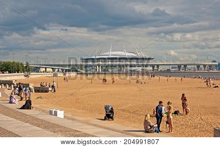 SAINT - PETERSBURG, RUSSIA - AUGUST 16, 2017: People on the beach in the 300 years St. Petersburg Anniversary Park. On the background is Krestovsky Stadium (Zenit Arena) by Kisho Kurokawa
