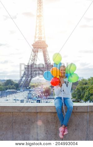 Happy girl with bunch of colorful balloons in Paris near the Eiffel tower.