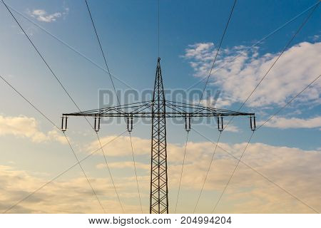 Silhouette of a high voltage tower at cloudy sky at sunset