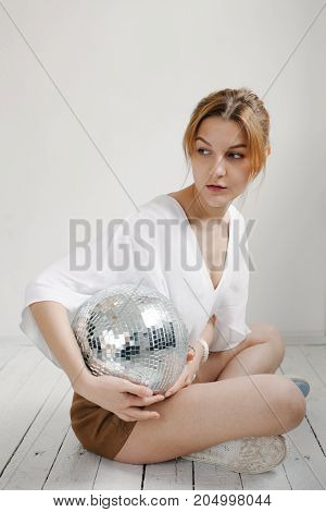 Young Hipster Woman Holding Disco Ball And Posing Cheerfully On White Background