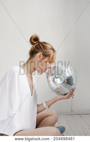 Young Hipster Woman Holding Disco Ball And Posing Cheerfully On White Background