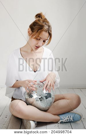Young Hipster Woman Holding Disco Ball And Posing Cheerfully On White Background
