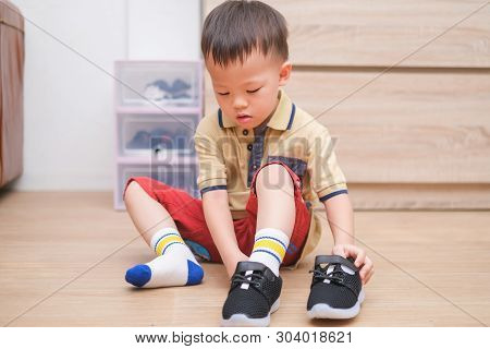 Little Asian 2 - 3 Years Old Toddler Boy Sitting And Concentrate On Putting On His Black Shoes / Sne