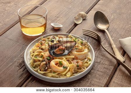 Seafood Pasta. Tagliolini With Mussels, Shrimps, Clams And Squid Rings, With A Glass Of Wine On A Da