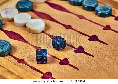 Backgammon Game. Game Dice Made Of Stone Lie On The Backgammon Board Against The Background Of Check