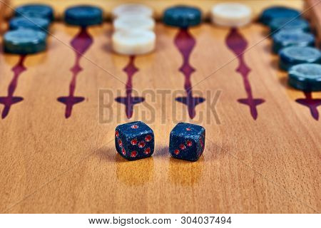 Backgammon Game. Game Dice Made Of Stone Lie On The Backgammon Board Against The Background Of Check
