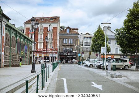 Lourdes, France - June 18, 2018: Place Du Champ Commun. Beautiful Old Buildings And Cars Park Near T