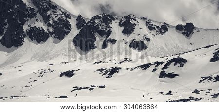 Panoramic View On High Mountains With Snow Cornice And Avalanche Trail, Snowy Plateau And Two Small 