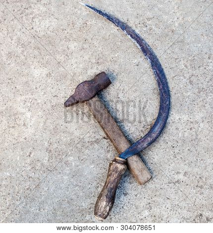 Sickle And Hammer (serp I Molot). Communist Symbol. Farm And Worker Tools On The Concrete Surface.