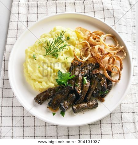 Close Up Of Mashed Potatoes With Roasted Beef Liver And Fried Onion Rings On White Plate. Pieces Liv
