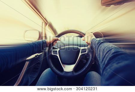 Closeup Of Man Driver Hands Holding Tight The Steering Wheel Of His New Car, Moving Fast. Motion Blu