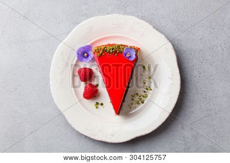 Raspberry Layerd Cake Decorated With Violet Flowers On White Plate. Grey Stone Background. Top View