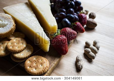 Cheese On A Wooden Board. Cheese, Tomatoes, Grapes And Cracker. Cheese Design. Cheese With Strawberr