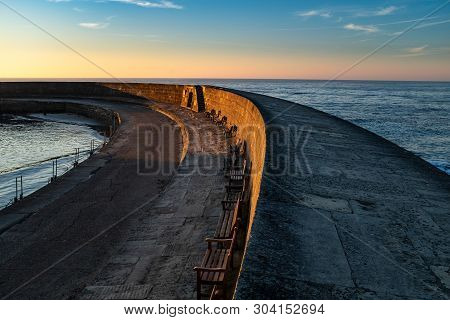 An Early Morning Photo Of The Cobb At Lyme Regis Sweeps Out To Sea, With The Sun Rising And The Sky 