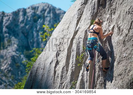 Rock Climbing And Mountaineering In The Paklenica National Park. A Woman Overcomes A Challenging Cli