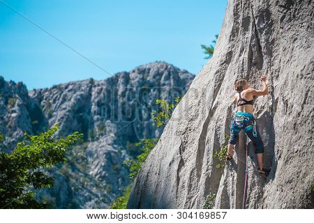 Rock Climbing And Mountaineering In The Paklenica National Park. A Woman Overcomes A Challenging Cli