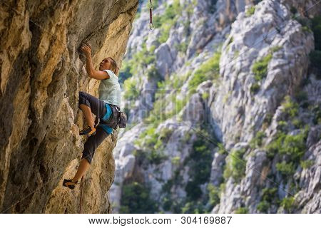 Rock Climbing And Mountaineering In The Paklenica National Park. A Woman Overcomes A Challenging Cli