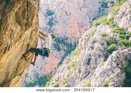 Rock Climbing And Mountaineering In The Paklenica National Park. A Woman Overcomes A Challenging Cli