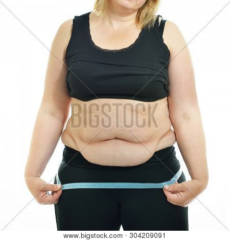Overweight unhappy middle-aged woman measuring her hips, isolated over white background. Overeating xxl size woman with measuring tape