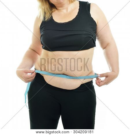 Overweight unhappy young woman measuring her waist, isolated over white background. Overeating xxl size woman with measuring tape