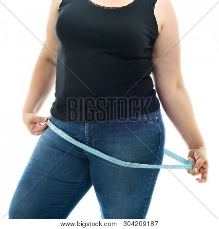 Overweight unhappy young woman measuring her hips, isolated over white background. Overeating xxl size woman with measuring tape