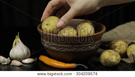 Potatoes On Black Surfase On A Plate. Fresh Potato With Traces Of Earth On The Skin. Dirty Raw Potat