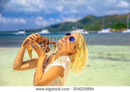 Tourism In Seychelles, Africa, Indian Ocean. Happy Tourist Woman Holding An Ocypode Ceratophthalmus 