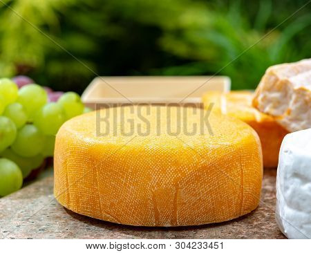 French Cheeses Collection, Yellow  Le Peche Des Bons Peres Cheese Served With Grapes On Marble Plate
