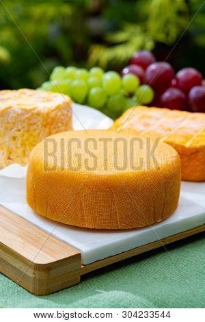 French Cheeses Collection, Yellow  Le Peche Des Bons Peres Cheese Served With Grapes On Marble Plate