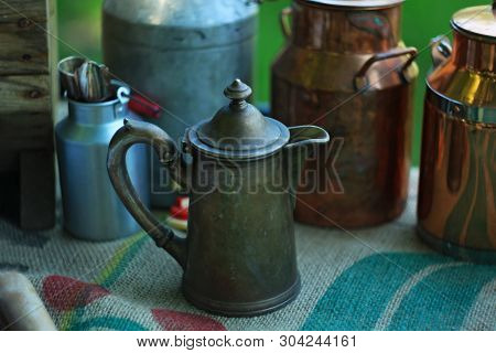 Antique Metal Jugs And Aluminum And Copper Milk Cans On Linen Tablecloth.