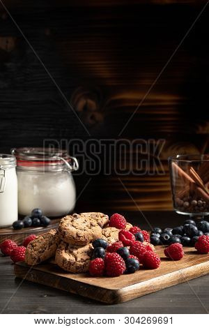 Fresh Berries Next To Chocolate Cookies Over Wooden Background