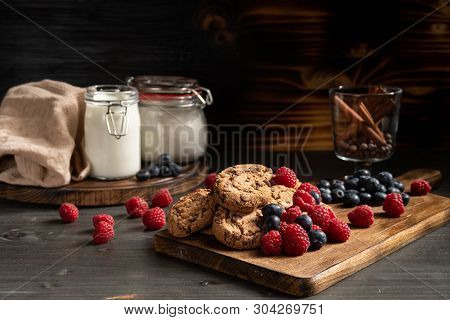 Cookies On Wooden Board Next To Berries And Cinnamon Sticks