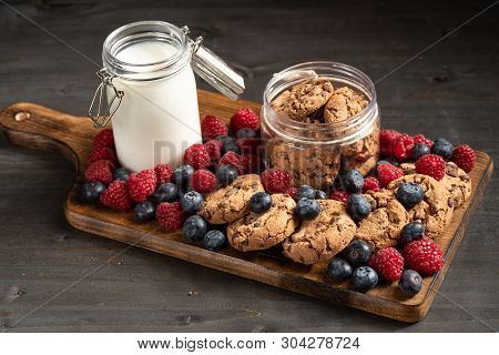 Lots Of Forest Fruits, A Jar Of Milk And Cookies, Placed Over Wooden Platter