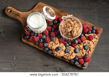 Table Top View Of Forest Fruits And Homemade Cookies Placed On Wooden Board.