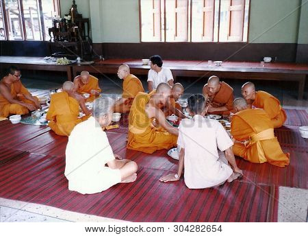 Bangkok, Thailand / Circa 2000: Buddhist Monks Enjoy A Meel While Seated On The Floor At A Buddhist 