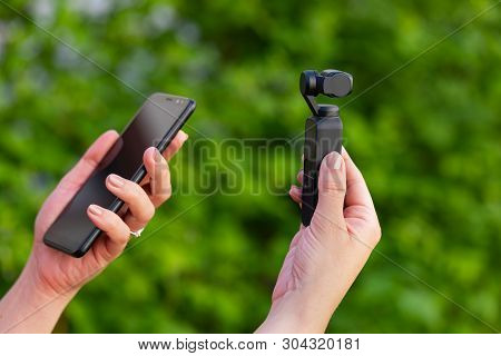 Close Up Picture Of Osmo Videographer And Smart Phone In Female Hands, Green Background