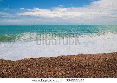 Beautiful Wild Beach With Azure Sea, Waves With White Foam And Pebbles On The Shore In Gargano, Ital