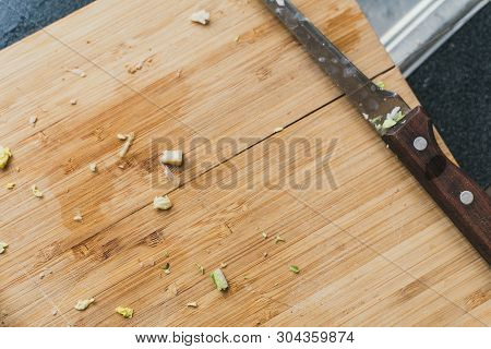 Dirty Wooden Cutting Board With A Knife. Remnants Of Greenery On A Wooden Background.