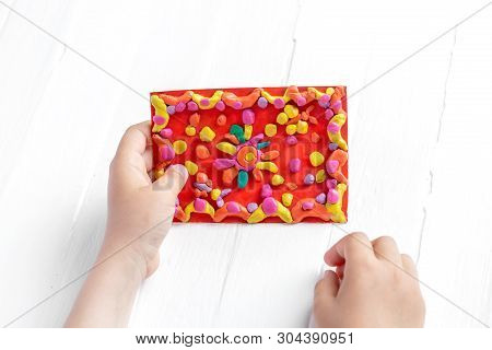 The Child Shows A Juicy, Bright Multi-colored Rug Made Of Plasticine.