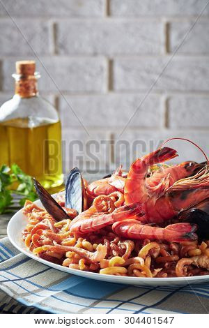 Spanish Fideua, A Noodle Paella With Prawns, Fish, Calamari, Mussels Served On A White Plate On A Gr