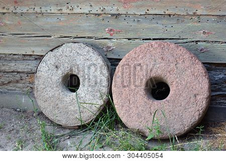 Two Millstones On Old Wooden Wall Background